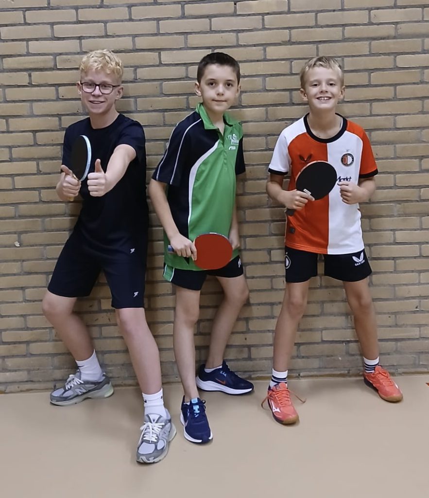 Drie jeugdspelers van Duo 2 pupillen met batje voor een bakstenen muur